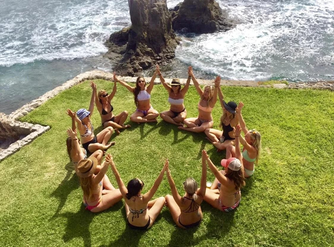 A yoga community gathering in a circle beside the ocean