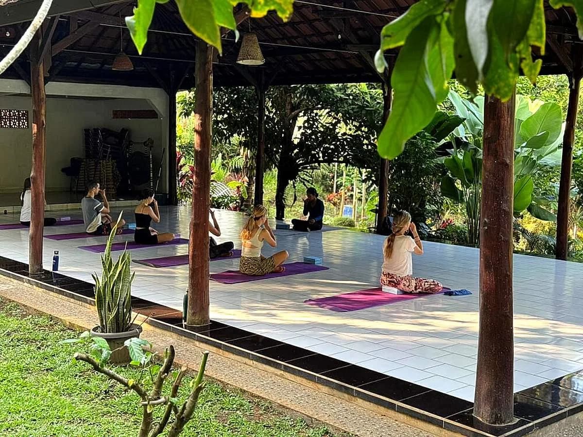 A yoga gathering in an open-air retreat pavilion surrounded by greenery