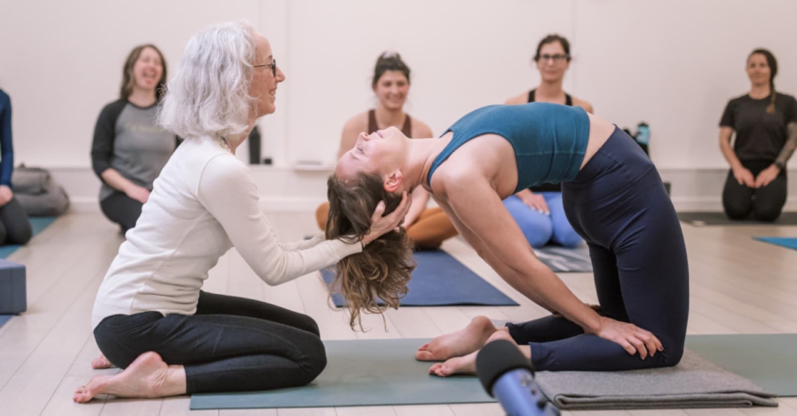 Annie Carpenter assisting a yoga practitioner in a supported backbend during an official SmartFLOW training