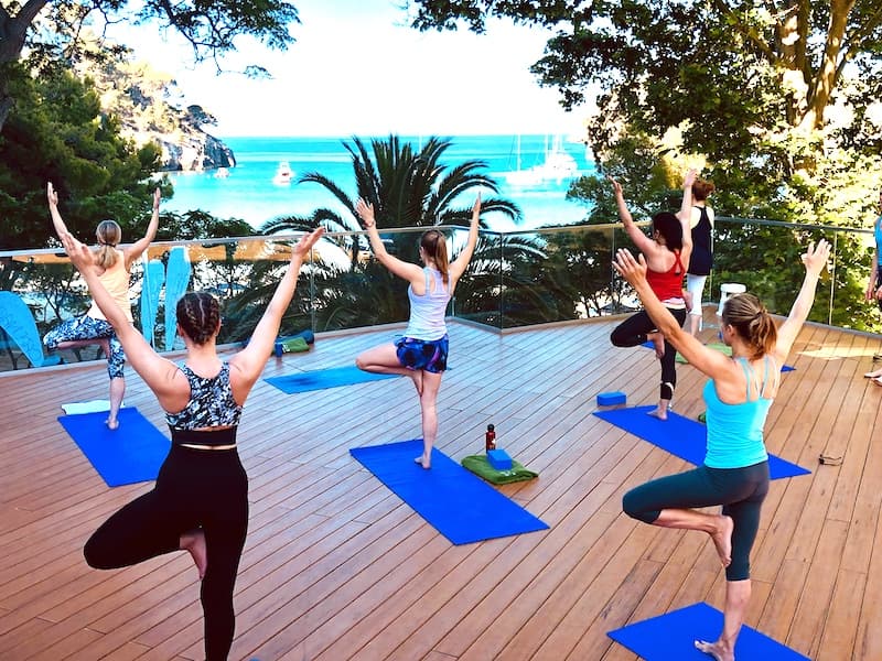 Yoga Escapes guests practicing outdoors above Cala Galdana beach in Menorca
