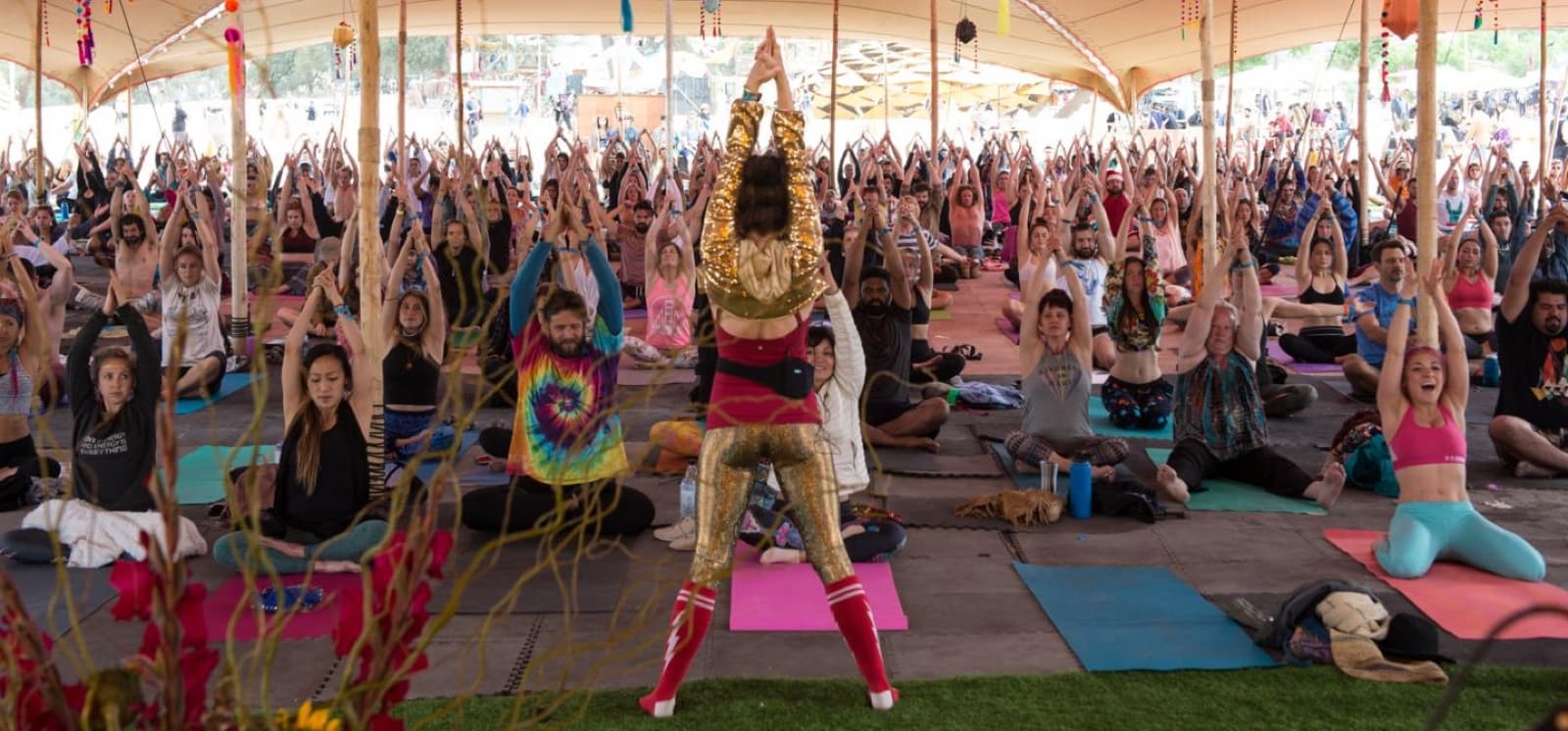 A large yoga gathering practicing together beneath a pavilion in the official Chakra Radiance event photograph